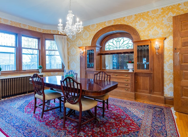 dining area featuring hardwood / wood-style floors, radiator heating unit, crown molding, and an inviting chandelier