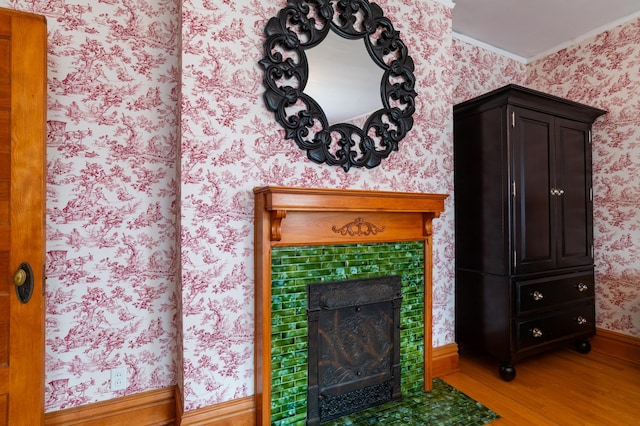 interior details featuring hardwood / wood-style flooring, crown molding, and a tiled fireplace