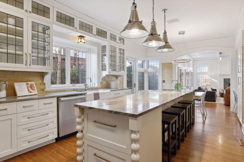 kitchen with pendant lighting, a center island, white cabinets, stainless steel dishwasher, and plenty of natural light