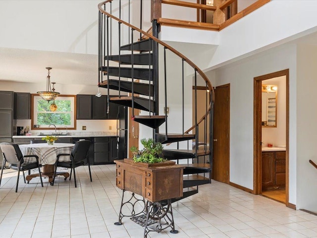 stairs featuring a high ceiling, a chandelier, sink, and tile patterned floors