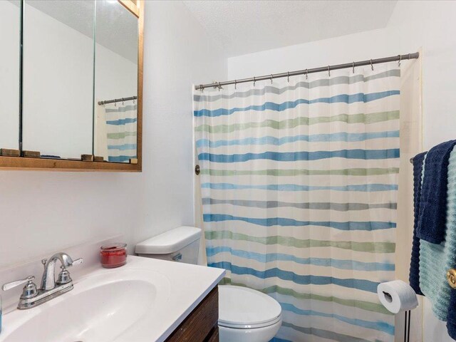 bathroom featuring a textured ceiling, vanity, toilet, and a shower with curtain