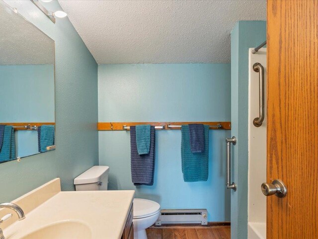 full bathroom featuring a textured ceiling, toilet, vanity, and baseboard heating