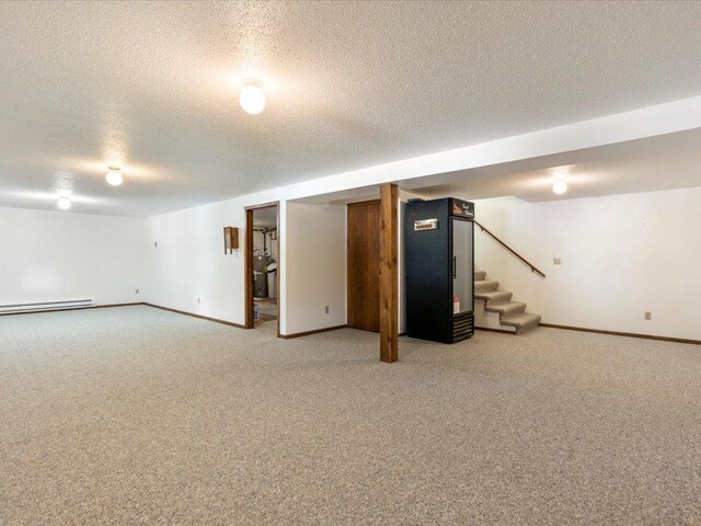 basement with a textured ceiling, a baseboard radiator, and carpet floors