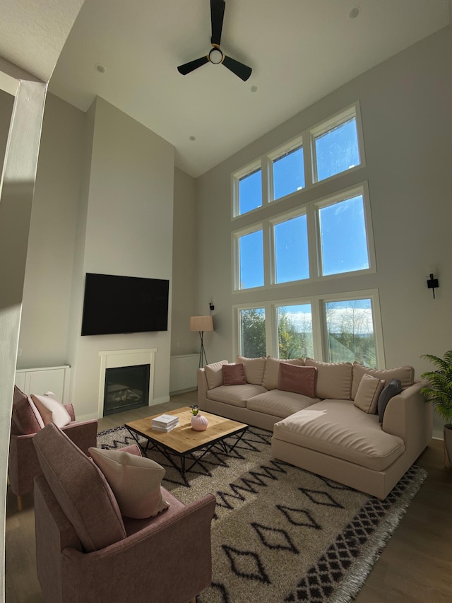 living room with a wealth of natural light, ceiling fan, a high ceiling, and hardwood / wood-style flooring