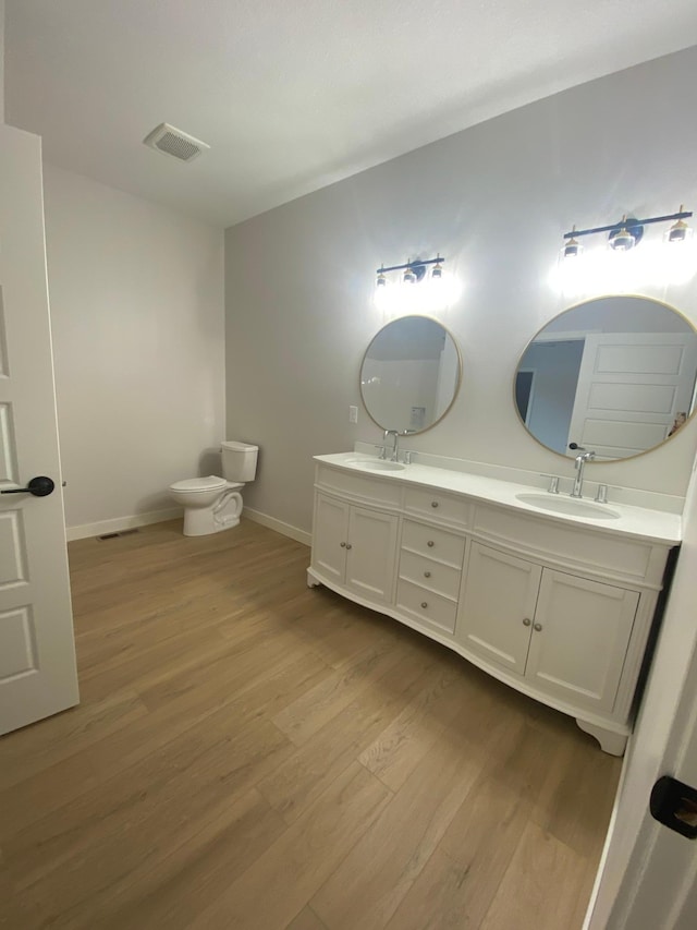 bathroom with dual sinks, hardwood / wood-style floors, oversized vanity, and toilet