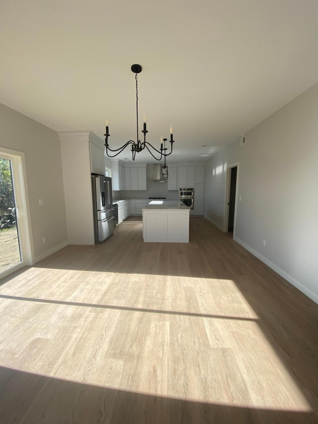 kitchen with stainless steel appliances, wood-type flooring, pendant lighting, and a kitchen island