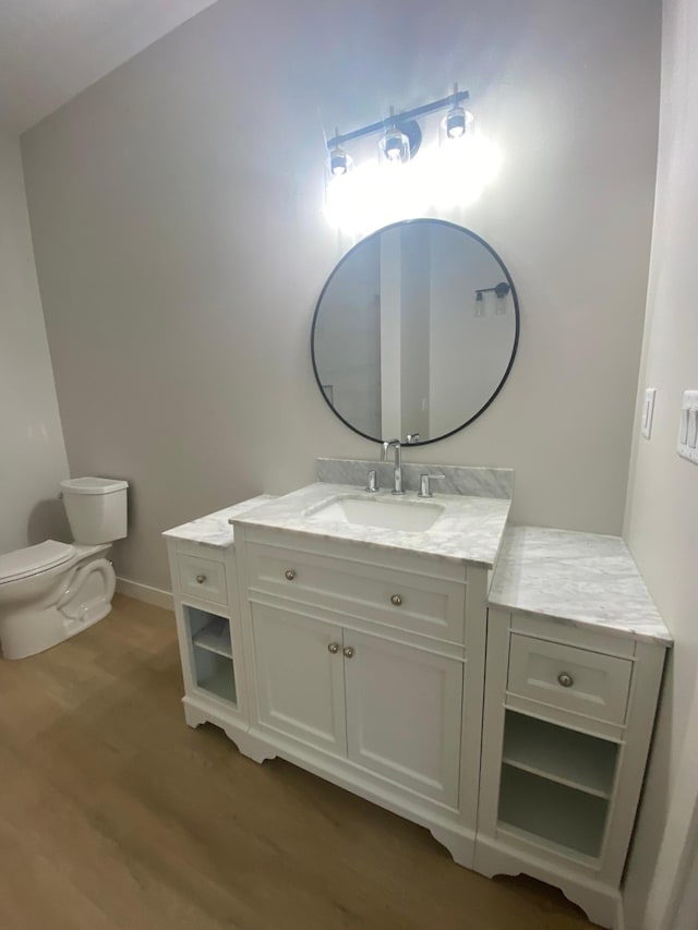 bathroom featuring vanity with extensive cabinet space, toilet, and wood-type flooring