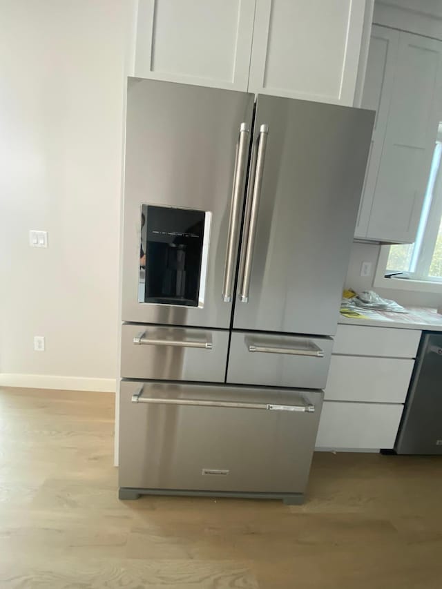 kitchen with light hardwood / wood-style floors, white cabinetry, stainless steel refrigerator with ice dispenser, and dishwashing machine