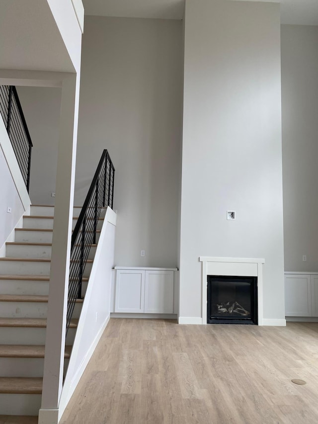 unfurnished living room with a high ceiling and light hardwood / wood-style flooring