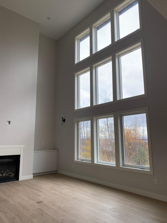 unfurnished living room with a high ceiling and light wood-type flooring