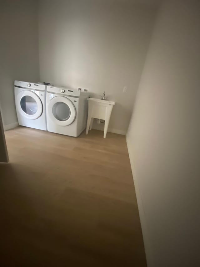 laundry area featuring wood-type flooring, separate washer and dryer, and sink