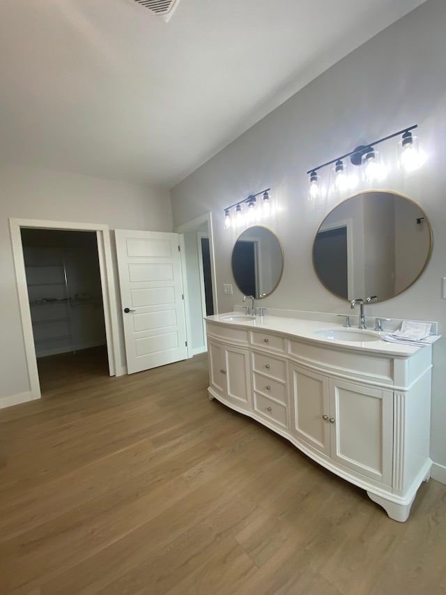 bathroom featuring wood-type flooring, oversized vanity, and double sink