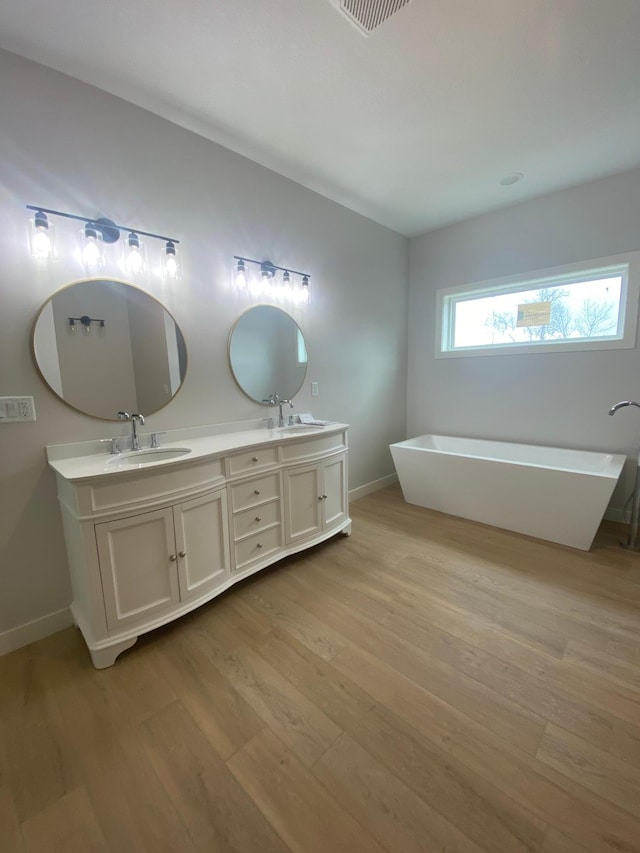 bathroom with dual vanity, wood-type flooring, and a bathing tub