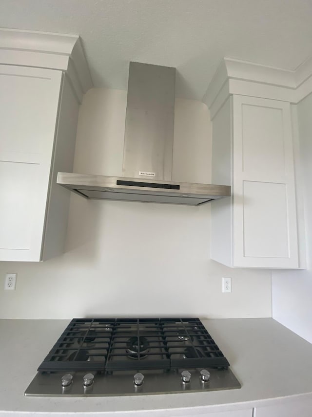 kitchen featuring wall chimney range hood and white cabinetry