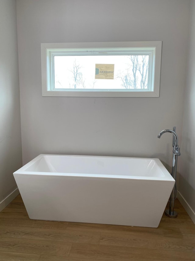 bathroom with hardwood / wood-style floors and a bath to relax in