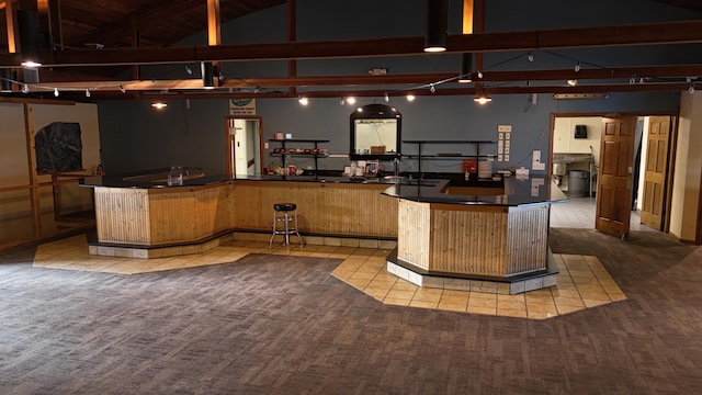 kitchen featuring high vaulted ceiling, beam ceiling, carpet floors, and a kitchen island with sink