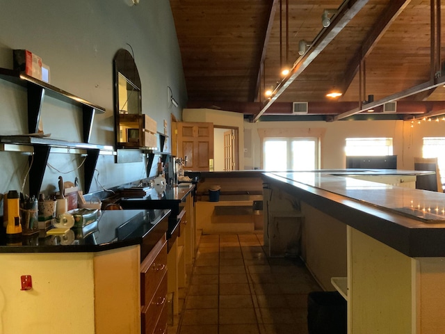 kitchen with vaulted ceiling with beams, wood ceiling, a large island, and dark tile patterned flooring