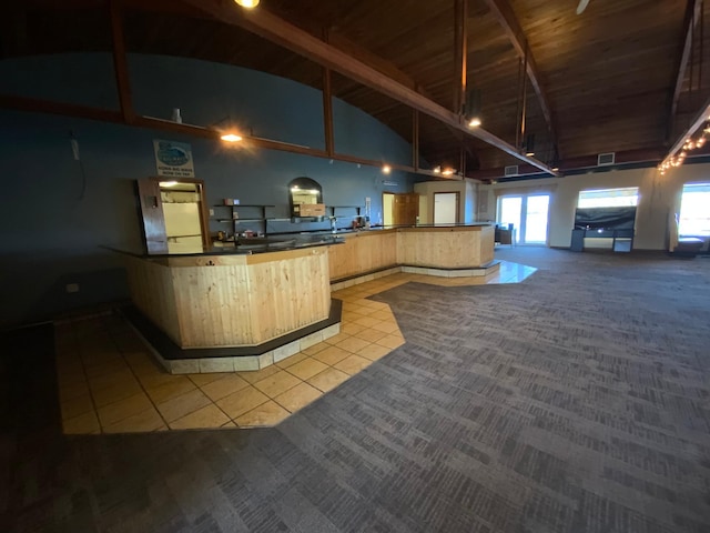 kitchen featuring beamed ceiling, high vaulted ceiling, light tile patterned floors, light brown cabinetry, and wooden ceiling