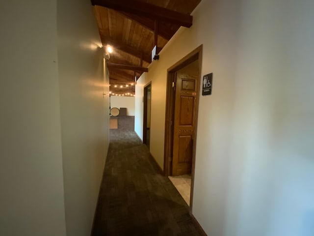 corridor with lofted ceiling with beams, wooden ceiling, and carpet floors