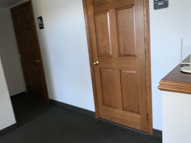 hallway featuring dark colored carpet