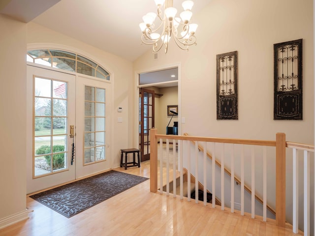 foyer entrance featuring a chandelier, french doors, light hardwood / wood-style floors, and vaulted ceiling