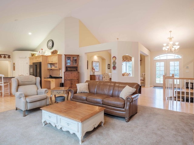 living room with light colored carpet, high vaulted ceiling, and a chandelier