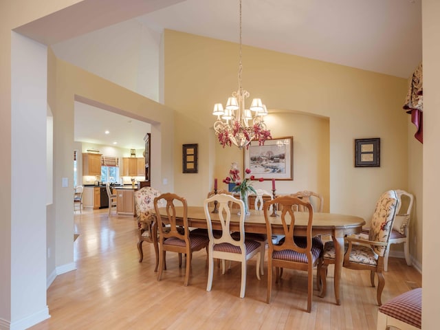 dining room with light hardwood / wood-style flooring, high vaulted ceiling, and a notable chandelier