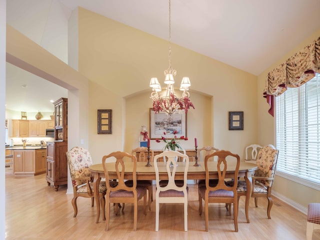 dining space featuring vaulted ceiling, a wealth of natural light, a notable chandelier, and light wood-type flooring