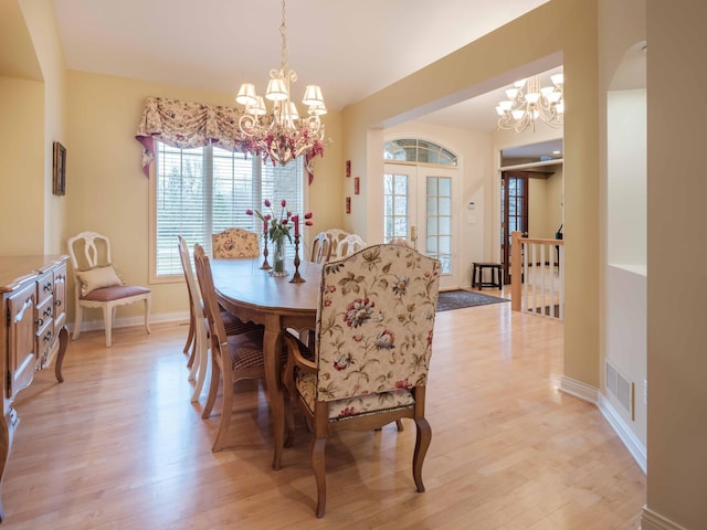 dining area featuring light hardwood / wood-style flooring, french doors, and a notable chandelier