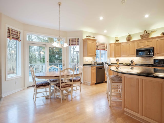 kitchen with a healthy amount of sunlight, hanging light fixtures, stainless steel appliances, and light wood-type flooring