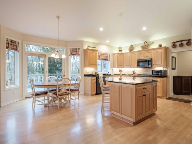 kitchen with light brown cabinetry, light wood-type flooring, a kitchen island, and hanging light fixtures