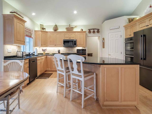 kitchen with light brown cabinets, a kitchen island, stainless steel appliances, and light hardwood / wood-style flooring