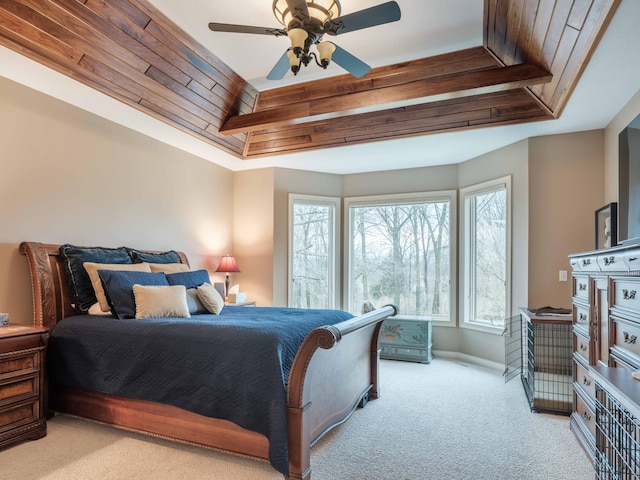 carpeted bedroom featuring a tray ceiling and ceiling fan