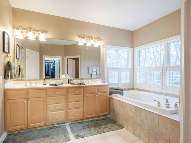 bathroom with vanity, a relaxing tiled tub, and tile patterned floors