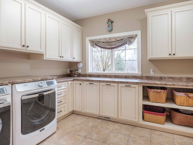 laundry room featuring cabinets, light tile patterned floors, and separate washer and dryer