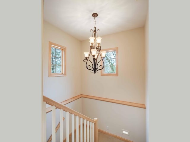 staircase featuring carpet flooring, plenty of natural light, and a chandelier