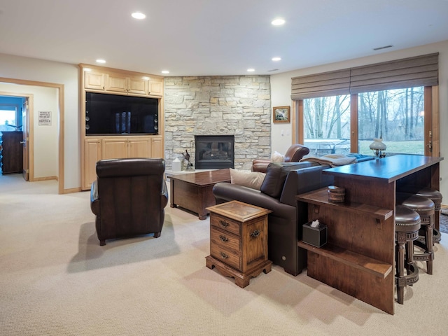 living room featuring light colored carpet and a stone fireplace