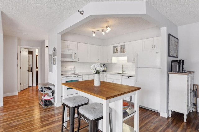 kitchen featuring white appliances, white cabinetry, dark hardwood / wood-style floors, rail lighting, and a textured ceiling