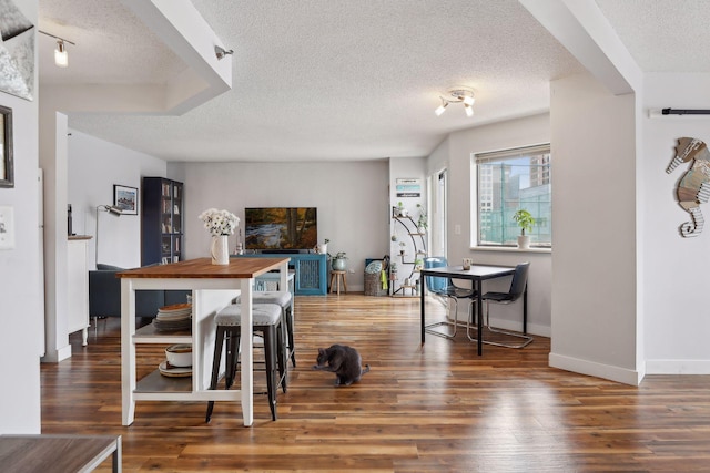 dining area with dark wood-type flooring and a textured ceiling