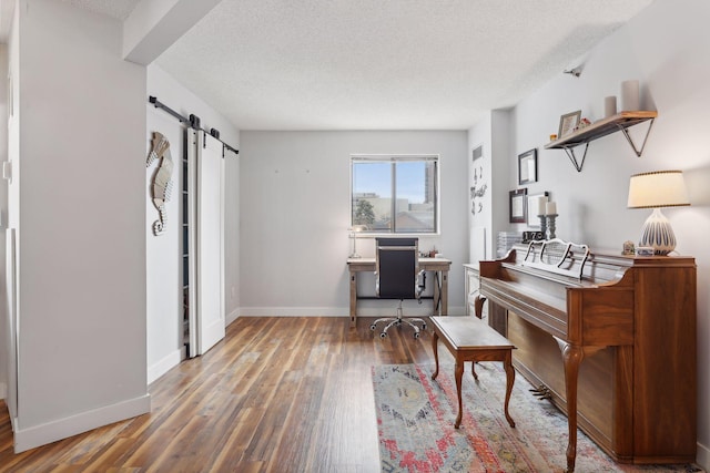 office featuring a textured ceiling, hardwood / wood-style flooring, and a barn door