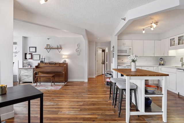 kitchen with a textured ceiling, white cabinets, white appliances, tasteful backsplash, and dark hardwood / wood-style floors