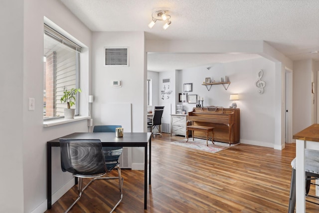 dining space with dark hardwood / wood-style flooring and a textured ceiling