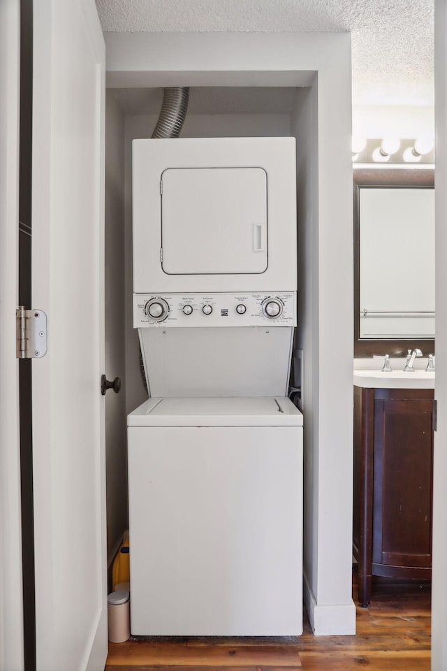 laundry room featuring dark hardwood / wood-style floors, a textured ceiling, washer hookup, and stacked washer / drying machine