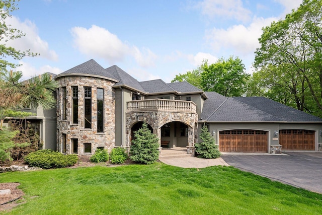 view of front of home with a garage, a front lawn, and a balcony