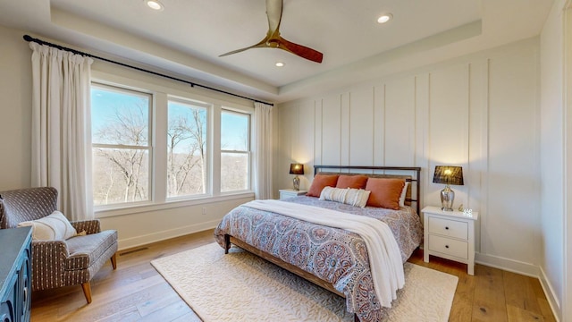 bedroom featuring a raised ceiling, ceiling fan, and light hardwood / wood-style floors