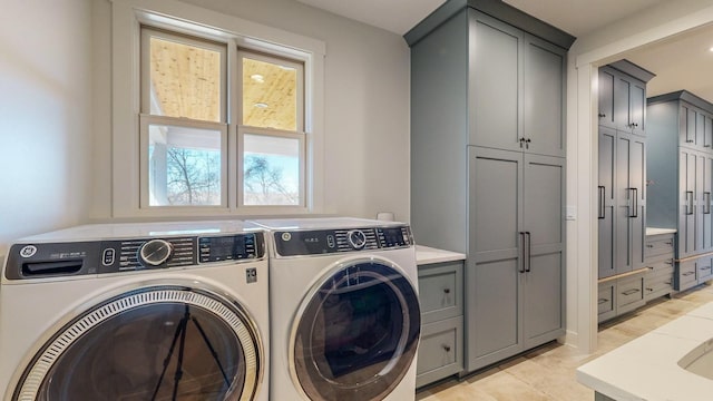 clothes washing area featuring cabinets and washing machine and dryer