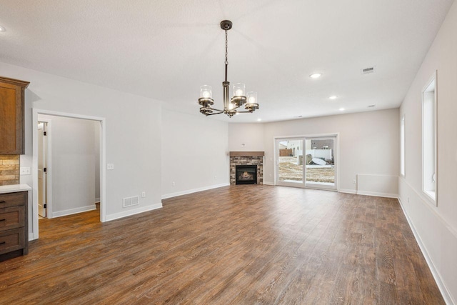 unfurnished living room featuring a chandelier, a fireplace, and dark hardwood / wood-style flooring