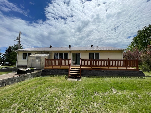 rear view of property featuring a lawn, an outdoor structure, and a wooden deck