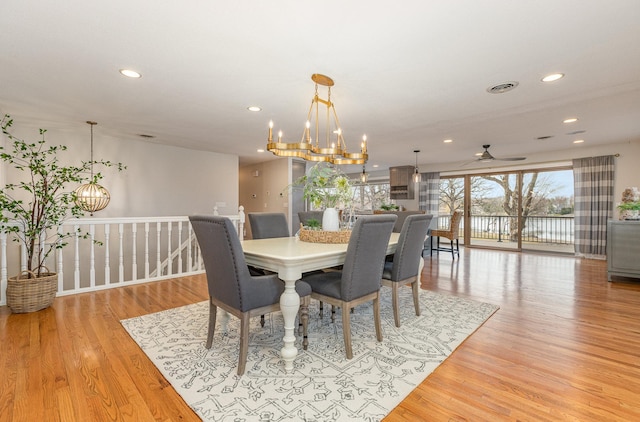 dining room featuring ceiling fan with notable chandelier and light hardwood / wood-style flooring