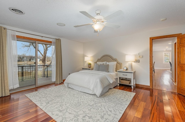 bedroom featuring ceiling fan, dark hardwood / wood-style floors, access to outside, and a textured ceiling